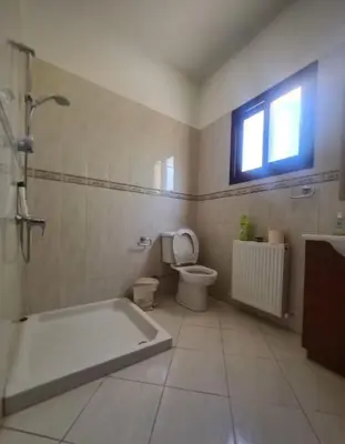 a bathroom with a tub and a toilet and a window at Maria's Garden House in Pelendri
