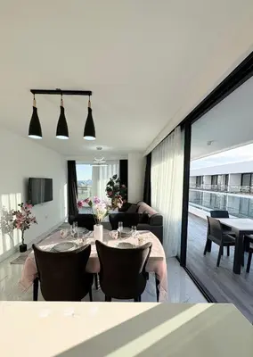 a dining room with two tables and a living room at Brand new 2 bedrooms apartment in Grand Sapphire in İskele