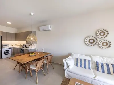 a kitchen and living room with a wooden table and chairs at Mythical seas 004 in Paralimni