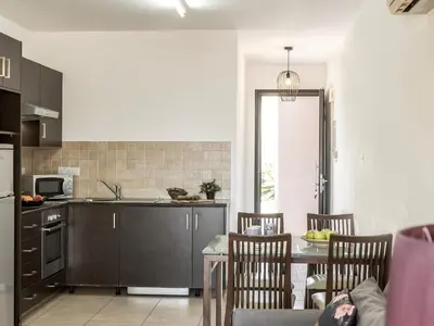 a kitchen with a table and chairs and a kitchen with a sink at Mythical Sands CB04 in Paralimni