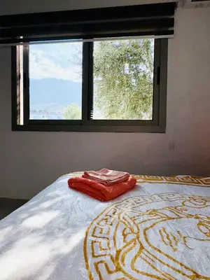 a bed with a red towel on it in front of a window at Orange Sunset Duplex Lapta 2 bedrooms close to Merit Casino in Meniko