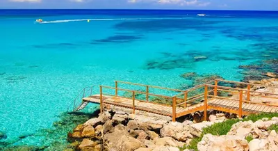 a wooden bench sitting on top of a body of water at Fig Tree Beach Villa One in Protaras