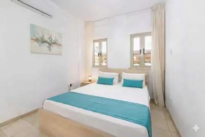 a bedroom with a large white bed with blue pillows at Fig Tree Beach villa Three in Protaras