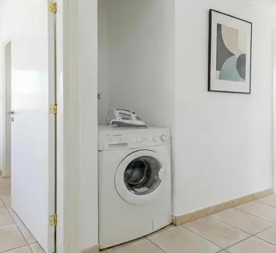 a washing machine in a white room with a phone at Fig Tree Beach villa Three in Protaras