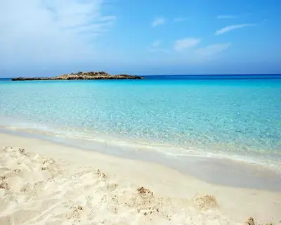 a sandy beach with an island in the ocean at Fig Tree Beach villa Three in Protaras