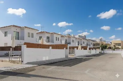 a row of houses behind a white fence at Fig Tree Beach villa Three in Protaras