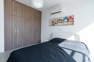 a bedroom with a bed and wooden cabinets at White Pearl Villa Protaras 7 in Paralimni