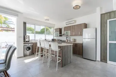 a kitchen with a refrigerator and a table and chairs at White Pearl Villa Protaras 7 in Paralimni