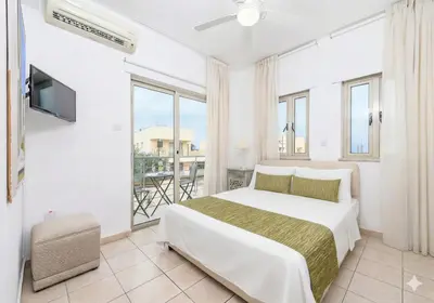 a white bedroom with a bed and a balcony at Fig Tree Beach Villa Four in Protaras