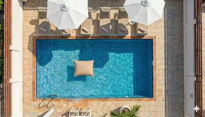 a swimming pool with two white umbrellas next to it at Fig Tree Beach Villa Five in Protaras