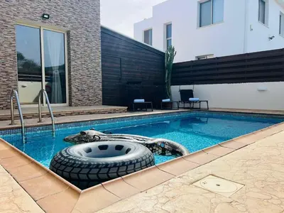 a swimming pool with a tire in the middle of it at Daffodil villa in Pernera in Protaras