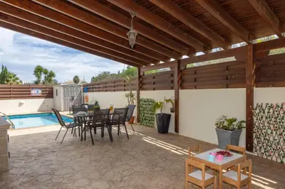 a patio with a table and chairs and a pool at Daffodil villa in Pernera in Protaras