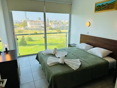 a bedroom with a green bed with a large window at Beachfront Seaview Apartment in Paralimni