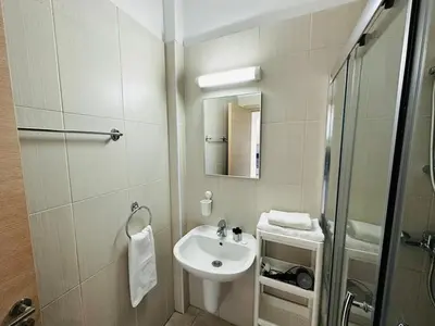 a white bathroom with a sink and a shower at Beachfront Seaview Apartment in Paralimni