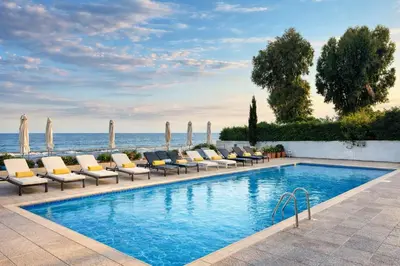 a swimming pool with lounge chairs and the ocean at Gulf Beach Apartment by TrulyCyprus in Limassol