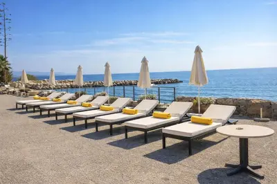 a row of lounge chairs with umbrellas and the ocean at Gulf Beach Apartment by TrulyCyprus in Limassol