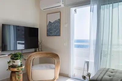 a living room with a television and a wicker chair at Compass 1-Bedroom Apartment in Larnaka