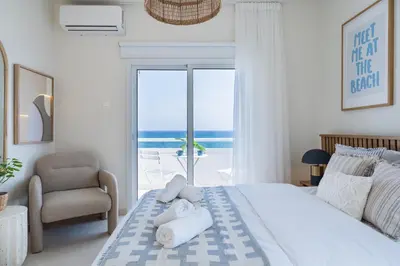 a bedroom with a bed with a chair and a window at Compass 1-Bedroom Apartment in Larnaka