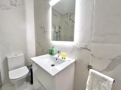 a white bathroom with a toilet and a sink at STAY Aelia Apartment in Nicosia