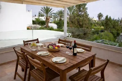 a wooden table with a bowl of fruit and wine bottles at Modern Seaside Apartment Steps to the Beach in Pervolia