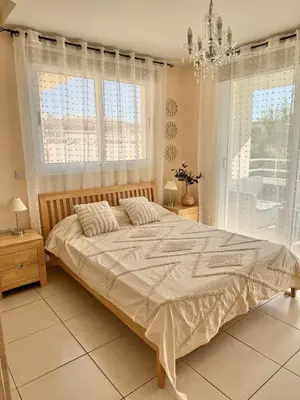 a bedroom with a large bed with windows and a chandelier at NISSI ELENA Family Apt FREE WIFI in Ayia Napa