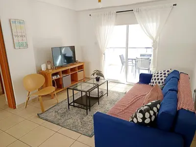 a living room with a blue couch and a tv at City Center Walking to the Beach 2 Bedrooms in Larnaka