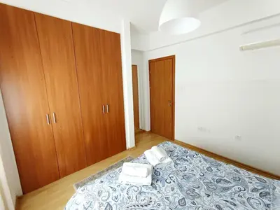 a bedroom with a bed with two towels and wooden cabinets at City Center Walking to the Beach 2 Bedrooms in Larnaka