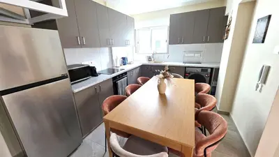 a kitchen with a wooden table and chairs in it at Warm Design 3BR, Beach 7-min walk, Peaceful in Larnaka