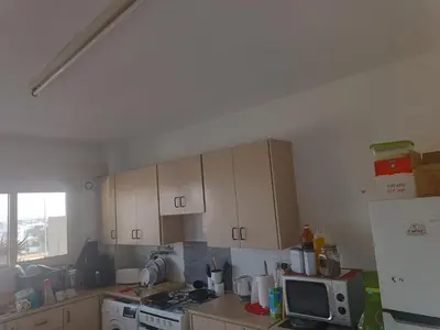 a kitchen with a stove and cabinets and a microwave at 1 room at sharing flat in Larnaka