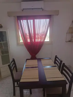 a dining room table with a red curtain and a window at 1 room at sharing flat in Larnaka