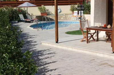 a patio with a table and an umbrella next to a pool at Luxury Villa Rental, Two Bedroom Villa with private pool and garden, in Pissouri