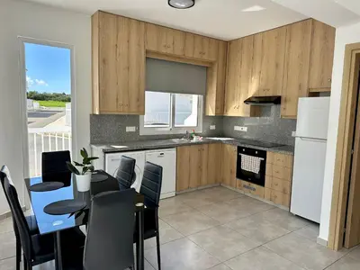 a kitchen with wooden cabinets and a table with chairs at Ocean Breeze 2BR House in Paralimni