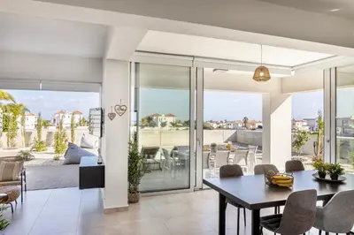 a living room with a table and chairs and a balcony at Protaras Hestia Seaside Villa A6 in Protaras