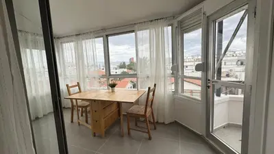 a table and chairs in a room with windows at The Perfect Lefkosa Stay - Zahra & Dereboyu & Ledra in Nicosia
