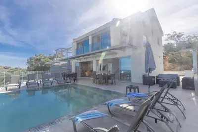 a house with a swimming pool with chairs and a house at Living the View in Protaras