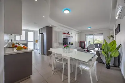 a kitchen and living room with a white table and chairs at Vasileos Konstantinou Modern 2BR City Apartment with Balcony in Limassol