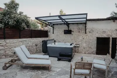 a patio with a tub and a chair and a table at Stonehouse in Monagri
