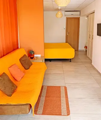 a living room with two yellow beds in a room at Rainbow Apartments in Ayia Napa