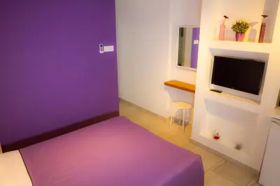 a purple room with a bed and a tv at Rainbow Apartments in Ayia Napa