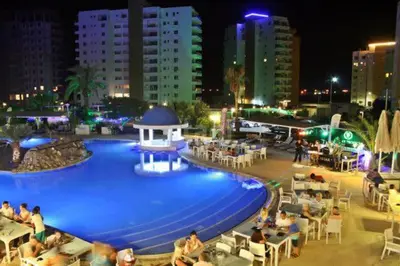 a large pool with people sitting around it at night at Sea view Remus Family 2 bdr apartment in Nicosia