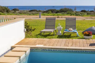 two chairs and a table next to a swimming pool at Protaras Seafront Villa Galene Del Mar in Protaras