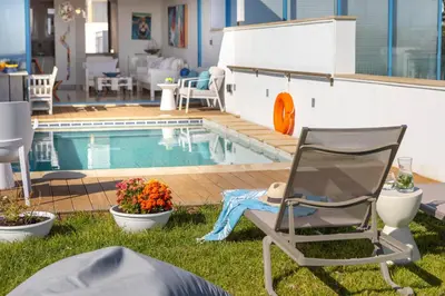 a chair sitting in the grass next to a swimming pool at Protaras Seafront Villa Galene Del Mar in Protaras