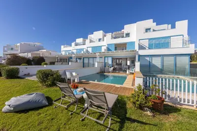a house with a swimming pool and two chairs at Protaras Seafront Villa Galene Del Mar in Protaras