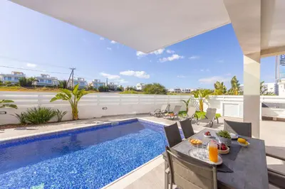an indoor pool with a table and chairs next to a house at Protaras Sol e Mar Villa 2 in Protaras
