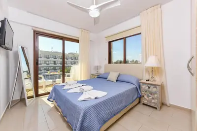 a bedroom with a blue bed and a balcony at Nissi Apartment #101 in Ayia Napa