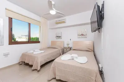 two beds in a room with a window at Nissi Apartment #101 in Ayia Napa