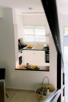 a kitchen with white cabinets and a plate of fruit on the counter at Kymo Fig Tree Bay House in Protaras