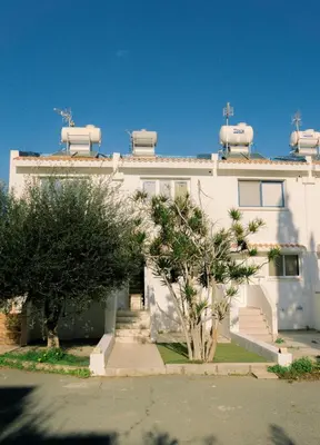 a white building with trees in front of it at Kymo Fig Tree Bay House in Protaras