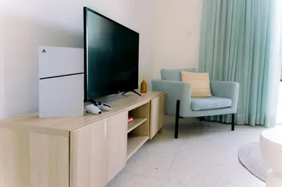 a living room with a flat screen tv and a chair at Kymo Fig Tree Bay House in Protaras