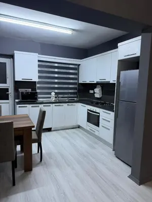 a kitchen with white cabinets and a wooden table with a tableablish at Royal Sun Comfortable Villa in Larnaka